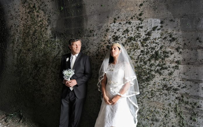 Актёры фильма «По млечному пути» стоят у стены в свадебных нарядах
